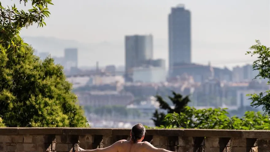 Un hombre toma el sol en un banco de un mirador de la montaña de Montjuic, en Barcelona, este viernes.
