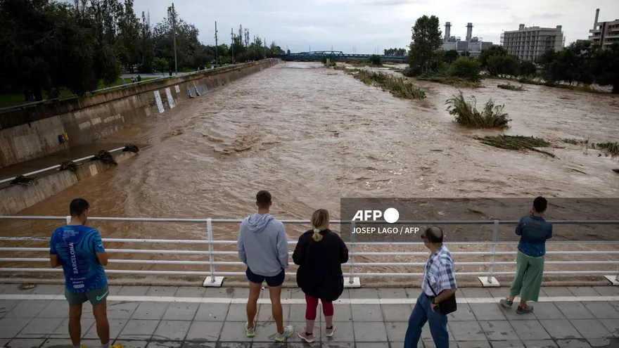 Personas observan la crecida de un río tras fuertes lluvias en España