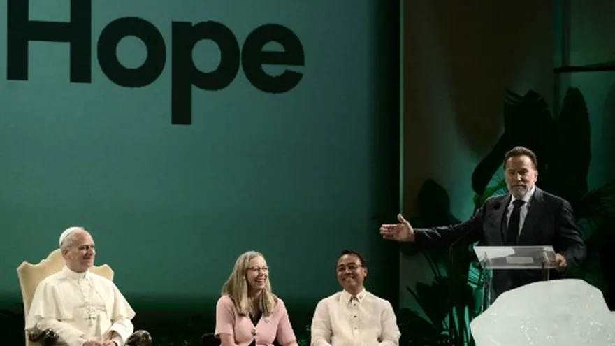 El papa León XIV (sentado) escucha a Arnold Schwarzenegger