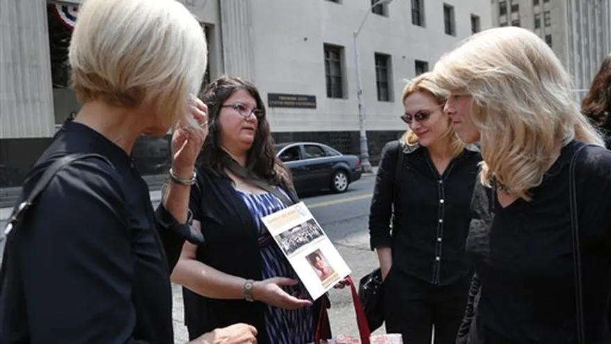 Liz Lupo, segunda izquierda, muestra un cartel que recuerda a su madre, Marianne Lupo, ex paciente del doctor Farid Fata, condenado por defraudar a pacientes y aseguradoras. Las víctimas hablaron en la corte, antes de pronunciarse la sentencia.