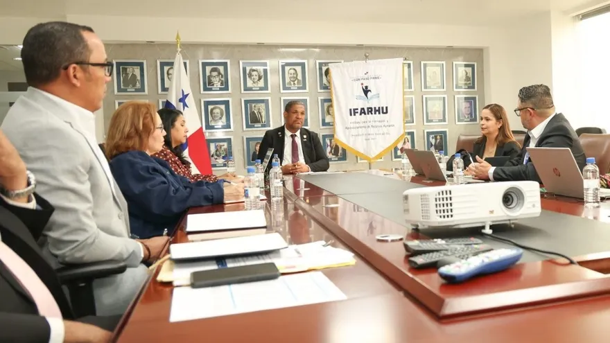 Reunión de trabajo en una sala de juntas del IFARHU, con el banderín de la institución y la bandera de Panamá.