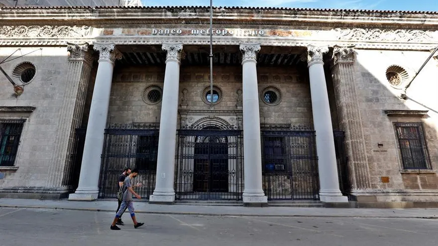 Dos personas caminan frente a una sede de un banco cerrado hoy en La Habana (Cuba).