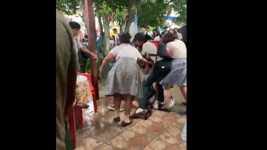 Momento en que una adolescente cae el piso mientras que otros estudiantes la golpean.