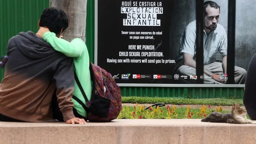 Una pareja se besa junto una imagen contra la explotación sexual infantil.