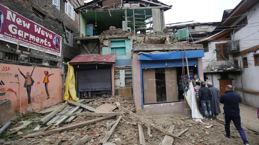 Un hombre camina cerca de unas viviendas dañadas en Srinagar, India, por el terremoto registrado hoy en la zona