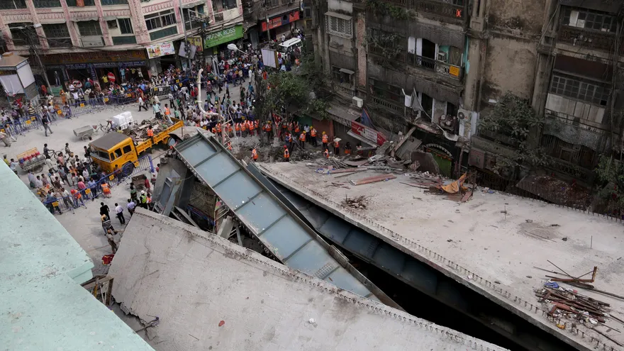 Efectivos de los servicios de rescate y personal del Ejército indio trabajan en la búsqueda de supervivientes bajo los escombros del puente en construcción que se derrumbó el jueves, en Calcuta, India.