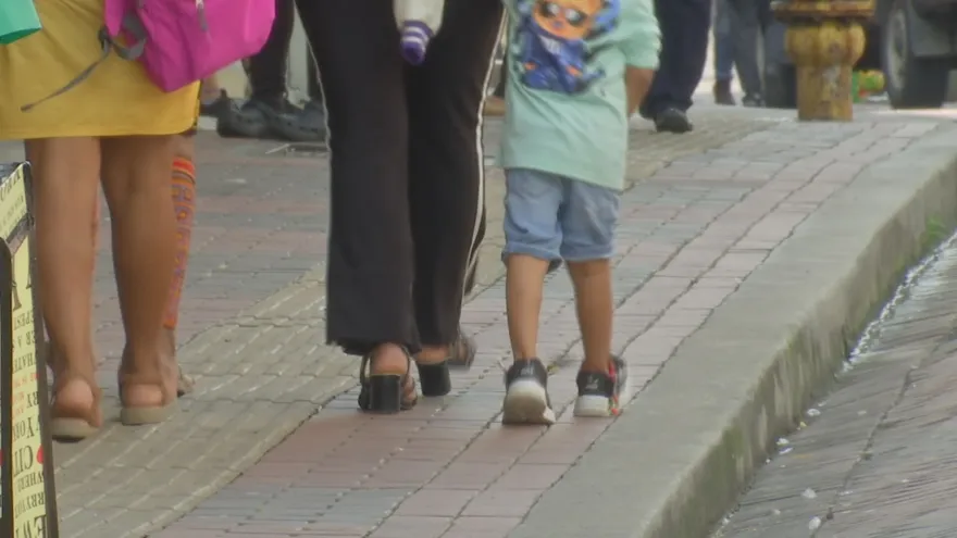 Un niño camina tomado de la mano de su mamá