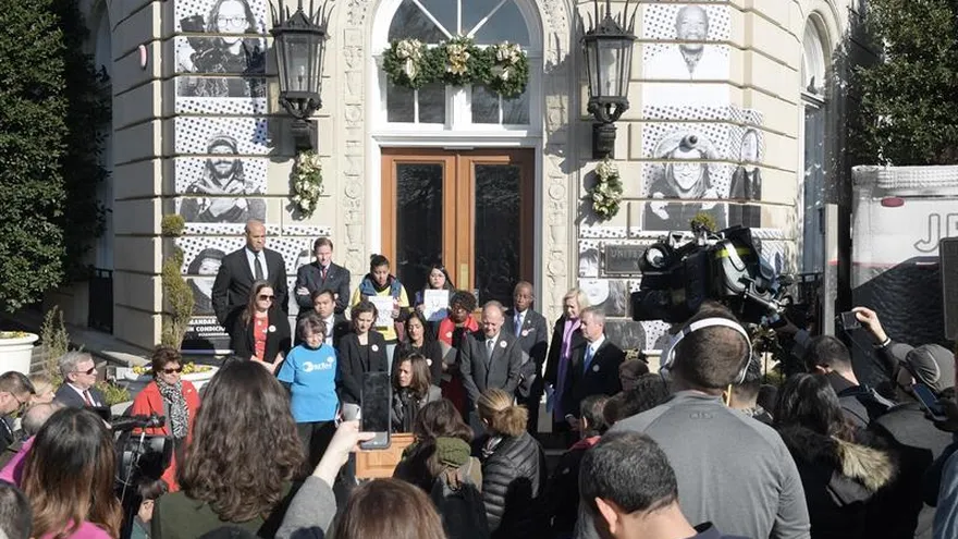 Unas personas escuchan a senadores y activistas hablar hoy, martes 19 de diciembre de 2017, en la puerta de una Iglesia Metodista a apenas unos metros del Congreso en Washington, DC, que tenía las paredes cubiertas con decenas de rostros de "soñadores" con el objetivo de reivindicar, también desde el arte, que el Legislativo dé una solución a esos jóvenes indocumentados.