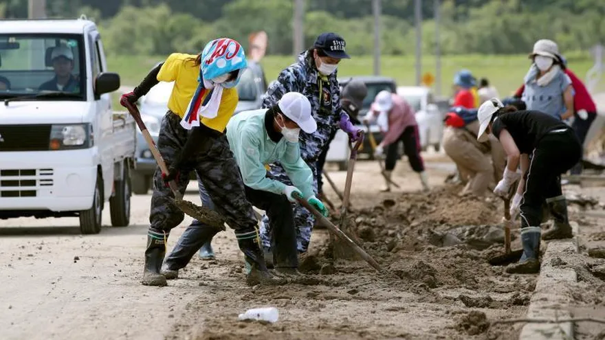 Varios residentes retiran barro de una zona arrasada por las inundaciones en la localidad de Kurashiki, prefectura de Okayama (Japón).