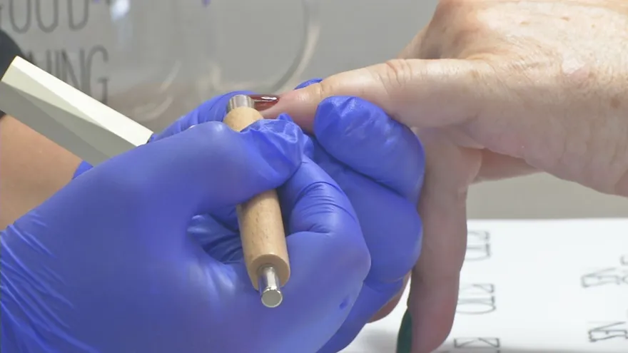 Una dependienta pinta las uñas a una clienta en un salón de belleza