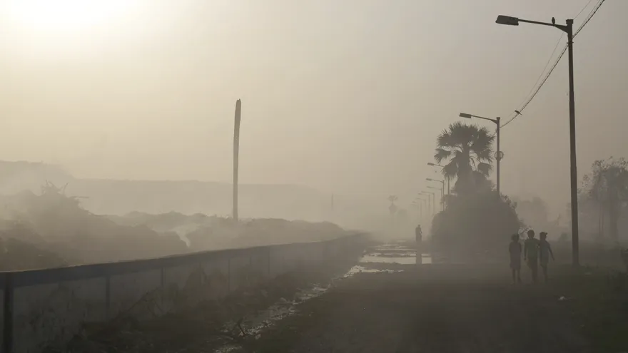 Varios niños caminan por una zona con un nivel alto de contaminación ambiental en un basurero de Calcuta (India)