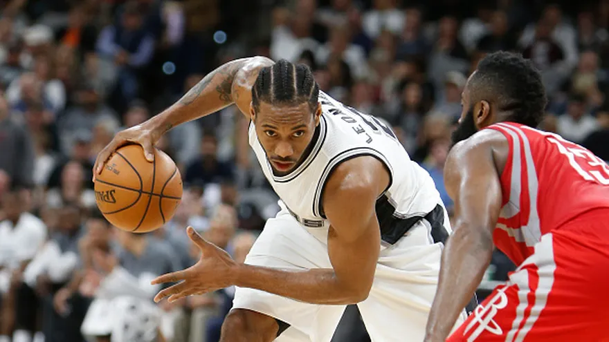 Kawhi Leonard (de frente) intenta evadir la cobertura de James Harden (de espalda)