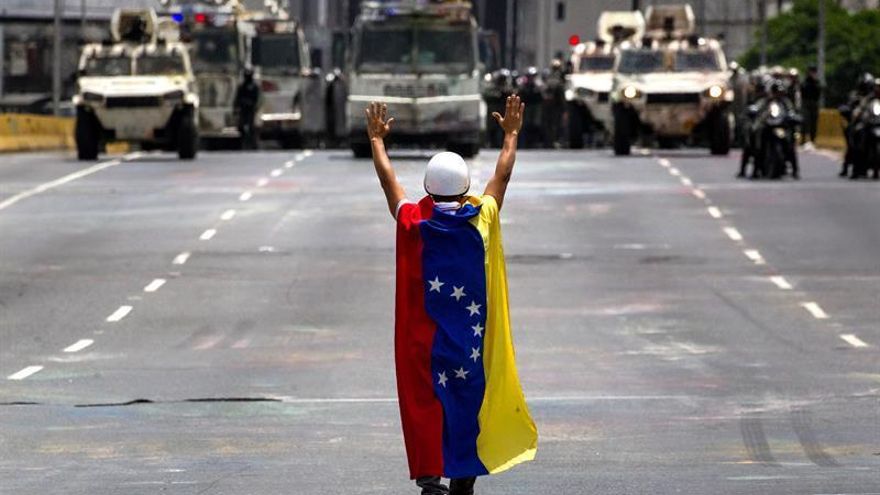 Un hombre permanece en frente de los vehículos de la Guardia Nacional Bolivariana (GNB) durante una manifestación opositora, el pasado miércoles 31 de mayo de 2017, en Caracas (Venezuela).