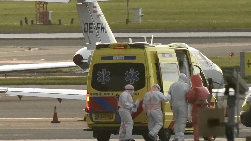 Una persona con traje de protección biológica (2R) es escoltada hacia una ambulancia desde una aeronave médica que presuntamente transporta a algunos de los pasajeros del crucero MV Hondius, considerados posibles infectados con hantavirus