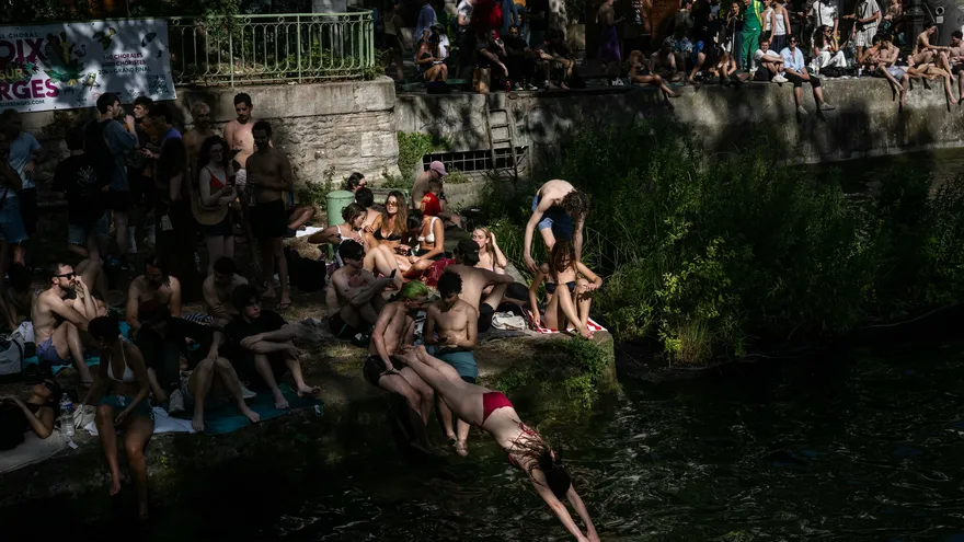 Un nadador se zambulle en el Canal Saint-Martin desde un lugar no autorizado para nadar, mientras Francia sufre una ola de calor.