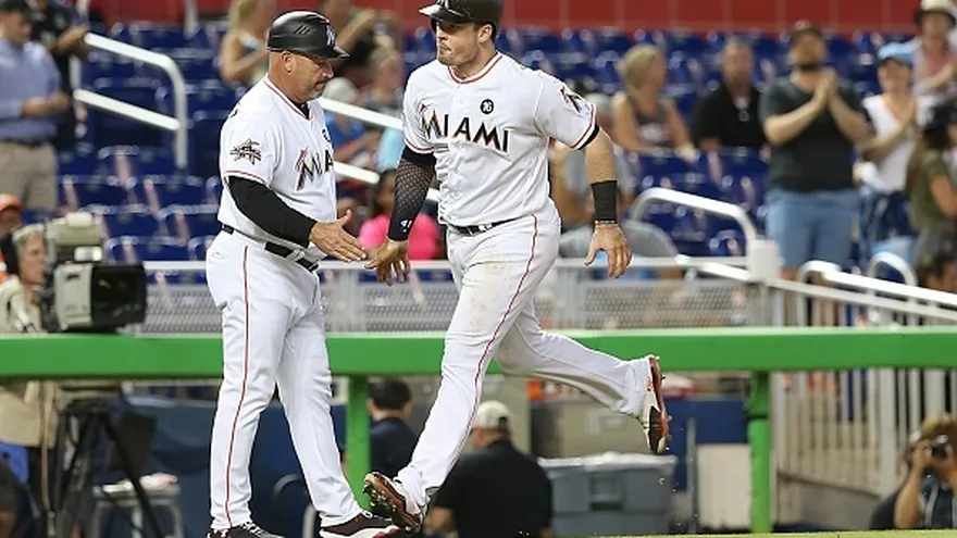 Justin Bour (d) es felicitado por el coach de tercera base Fredi González (i)