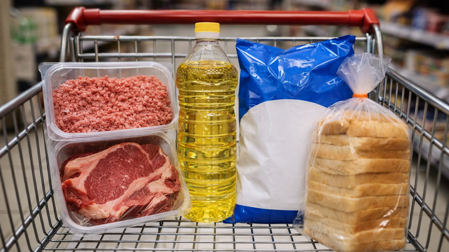 Un carrito de supermercado con una botella de aceite vegetal, leche en polvo, pan blanco de molde y carne molida