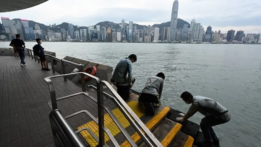 Los trabajadores se ven en el frente del puerto en Tsim Sha Tsui mientras Hong Kong se paraliza por segunda vez en menos de una semana cuando se acerca el ciclón tropical Kompasu.