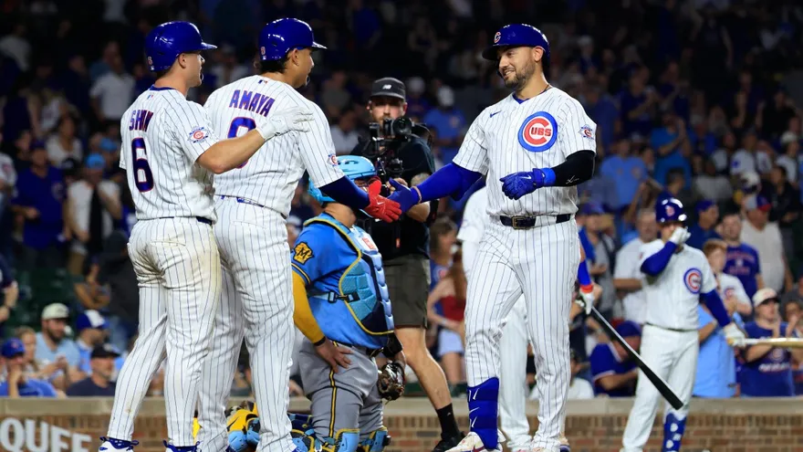 Miguel Amaya (c) y Matt Shaw (i) felicitan a Michael Conforto (d) quien conectó un cuadrangular en el partido entre Cachorros y Cerveceros