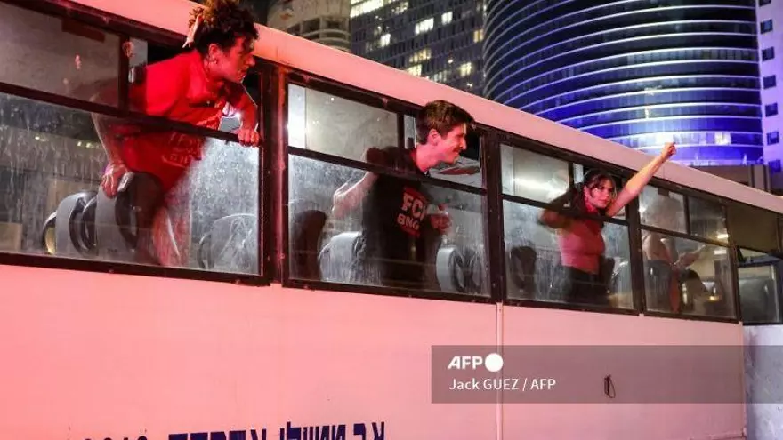 Manifestantes detenidos corean consignas desde el interior de un autobús policial tras una manifestación organizada por las familias de los rehenes israelíes tomados cautivos en la Franja de Gaza desde octubre de 2023 pidiendo acciones para asegurar su liberación, por el Centro Azrieli frente a la sede del Ministerio de Defensa en Tel Aviv el 9 de agosto de 2025.