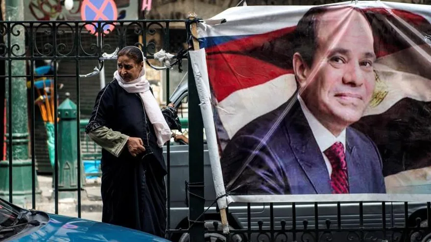 Una mujer camina junto a un cartel con la imagen del actual presidente egipcio y candidato presidencial, Abdelfatah al Sisi, en El Cairo, en Egipto.