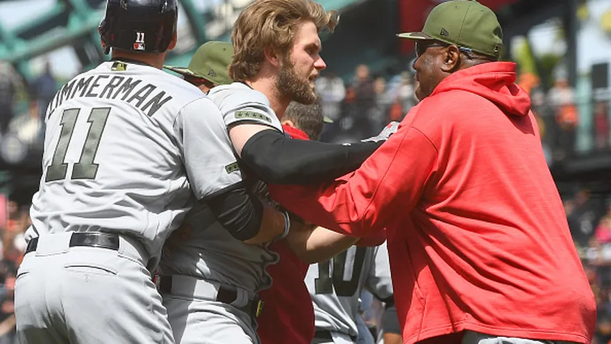Bryce Harper (c) fue apartado de la pelea por el manager Dusty Baker y su compañero Ryan Zimmerman (11)