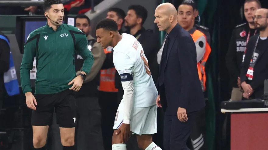 Un Kylian Mbappé adolorido pasa al lado de Zinedine Zidane, técnico de la selección de Francia