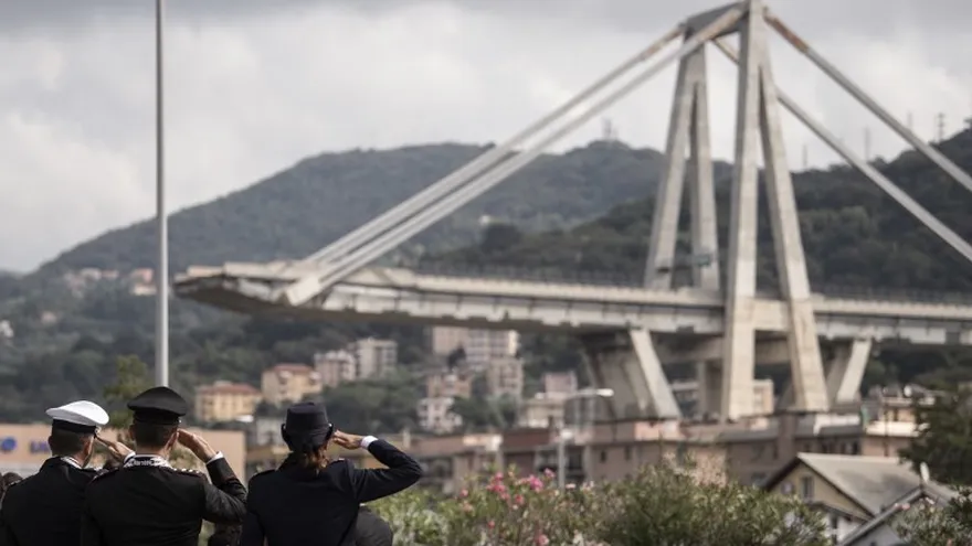 Miembros de la policía italiana rinden homenaje a las víctimas durante un minuto de silencio y una ceremonia de conmemoración cerca de los restos del puente, un mes después del colapso del puente Morandi.