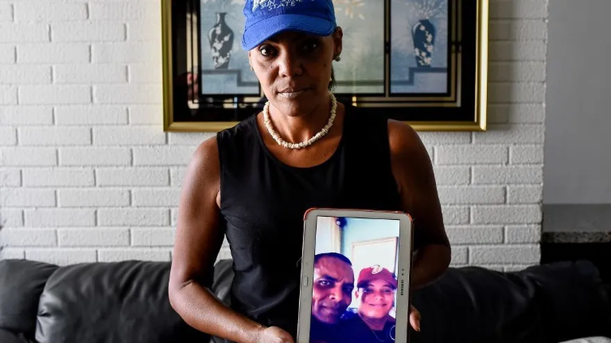 La venezolana Yamileth Marcano, de 46 años, muestra una tableta con la foto de su hermano, quien fue asesinado para robarle un teléfono celular.