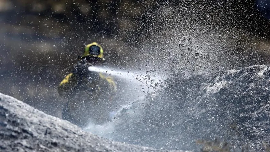 Un bombero trata de refrescar los puntos calientes dejados por el incendio denominado "Blue Cut Fire", al noreste de Los Ángeles, California, Estados Unidos hoy, 19 de agosto de 2016.